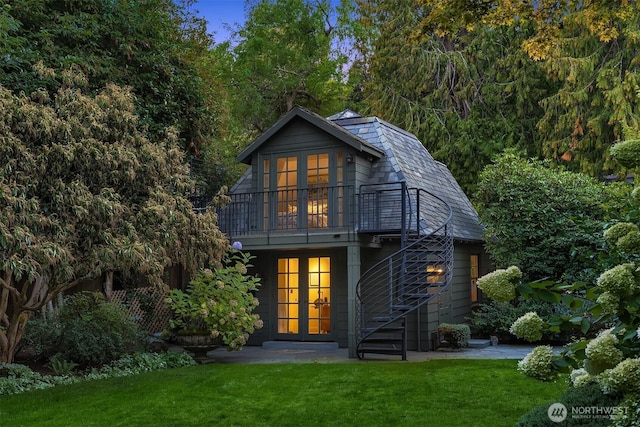 back of property featuring a lawn, a balcony, a high end roof, and stairs