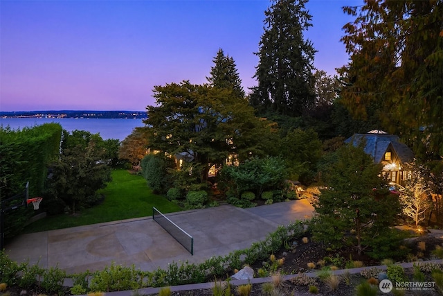 yard at dusk with a water view and a yard