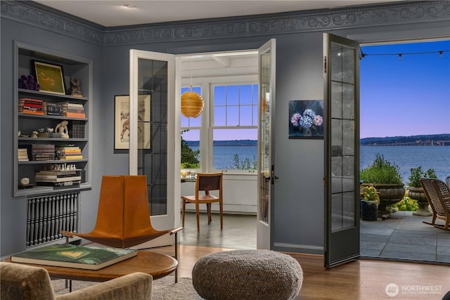 sitting room featuring radiator heating unit, wood finished floors, and a water view