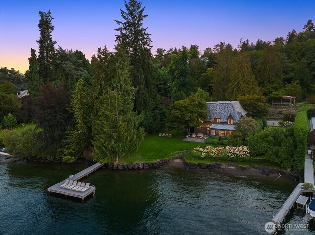 dock area featuring a water view, a forest view, and a lawn