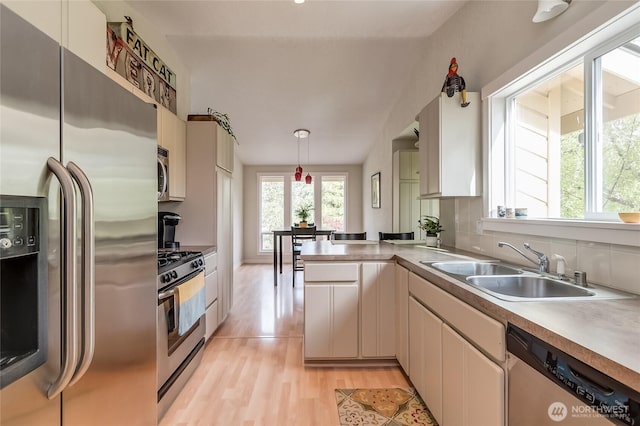 2217 W Birch, Bellingham, WA 98229 - kitchen featuring appliances with stainless steel finishes, a peninsula, pendant lighting, light wood-style flooring, and decorative backsplash