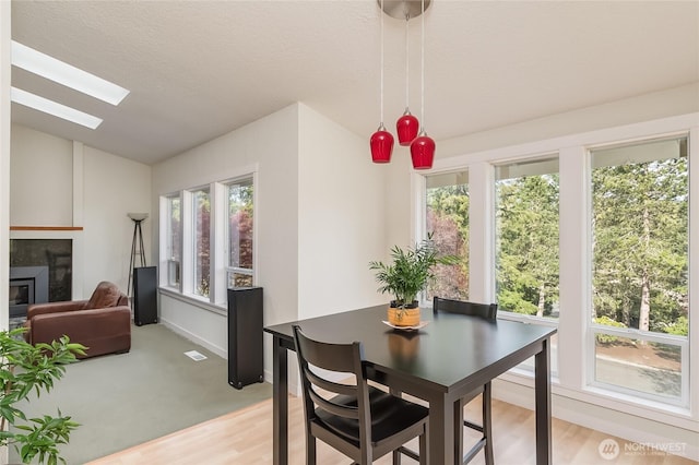 2217 W Birch, Bellingham, WA 98229 - dining space featuring vaulted ceiling, a skylight, a glass covered fireplace, and light wood finished floors