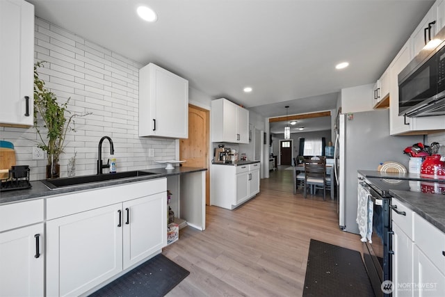 755 S Chelan Ave, Wenatchee, WA 98801 - kitchen featuring black range with electric cooktop, stainless steel microwave, dark countertops, white cabinets, and light wood-type flooring