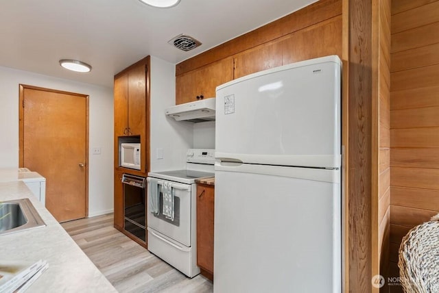 15633 47th Ave S, Tukwila, WA 98188 - kitchen featuring white appliances, under cabinet range hood, brown cabinets, light countertops, and light wood-type flooring