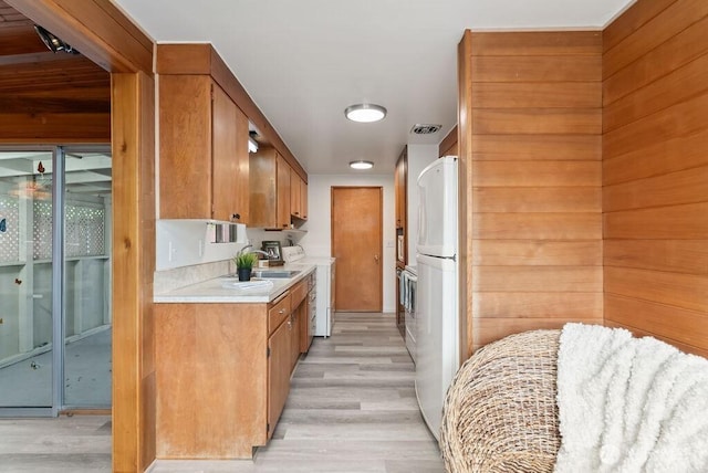 15633 47th Ave S, Tukwila, WA 98188 - kitchen with light countertops, light wood-style floors, freestanding refrigerator, and brown cabinetry