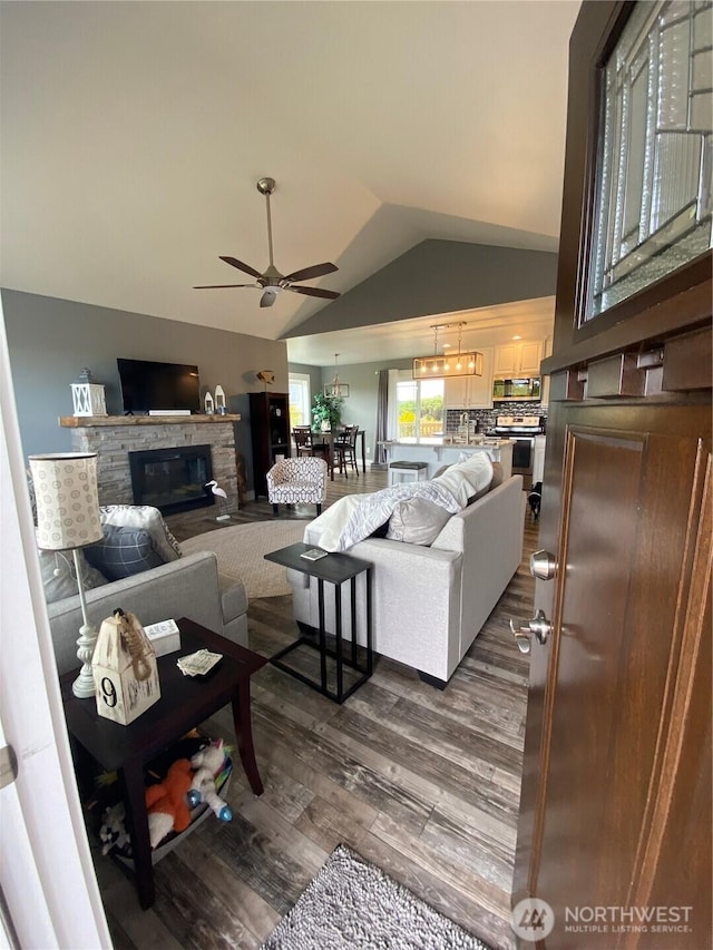1111 Riverside Ct, Ocean Shores, WA 98569 - living area with a ceiling fan, dark wood finished floors, vaulted ceiling, and a stone fireplace
