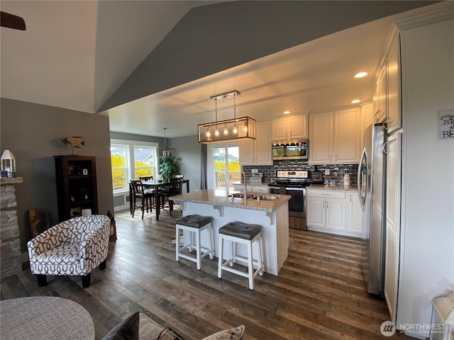 1111 Riverside Ct, Ocean Shores, WA 98569 - kitchen featuring appliances with stainless steel finishes, vaulted ceiling, dark wood finished floors, light stone countertops, and white cabinets