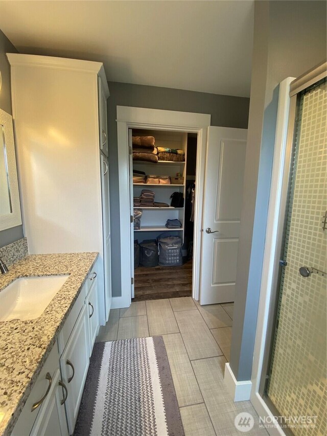 1111 Riverside Ct, Ocean Shores, WA 98569 - bathroom featuring vanity, a stall shower, a spacious closet, and wood finished floors