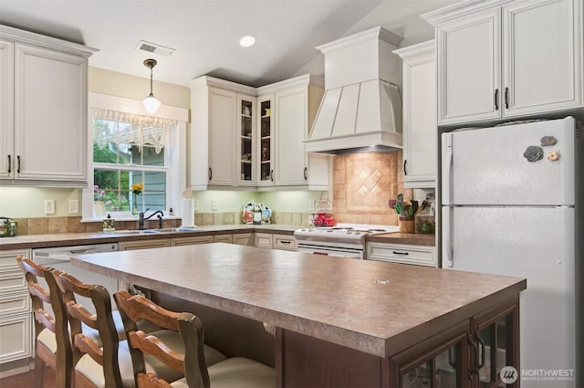 721 Abernathy Creek Rd, Longview, WA 98632 - kitchen featuring white appliances, custom range hood, a breakfast bar area, decorative backsplash, and a center island