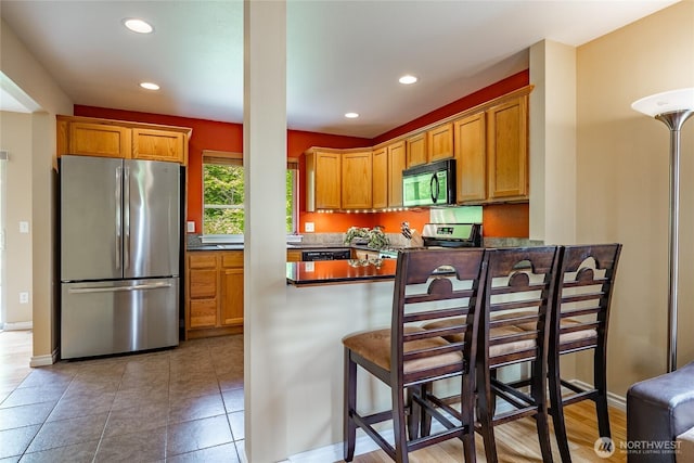 2740 Undine Pl, Bellingham, WA 98226 - kitchen with freestanding refrigerator, black microwave, dark countertops, stove, and a peninsula