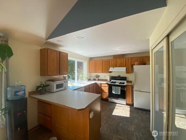 5846 SW 44th St, Port Orchard, WA 98367 - kitchen with white appliances, under cabinet range hood, a peninsula, light countertops, and brown cabinets