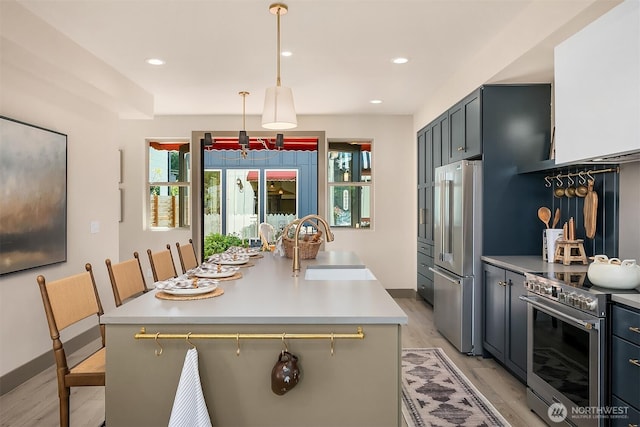 5037 25th Ave SW, Seattle, WA 98106 - kitchen with high quality appliances, light countertops, light wood-style flooring, a kitchen island with sink, and pendant lighting