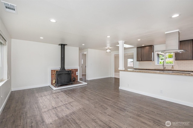 16812 125th Ave SE, Renton, WA 98058 - unfurnished living room featuring dark wood-type flooring, a wood stove, recessed lighting, and ornate columns