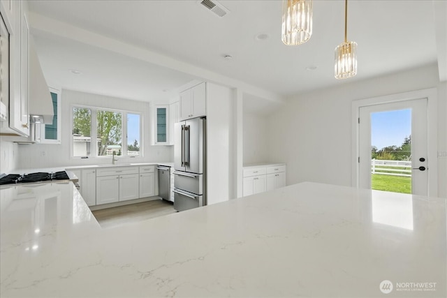 150 Cliff Robinson Ln, Sequim, WA 98382 - kitchen with stainless steel appliances, light stone counters, glass insert cabinets, white cabinetry, and decorative light fixtures