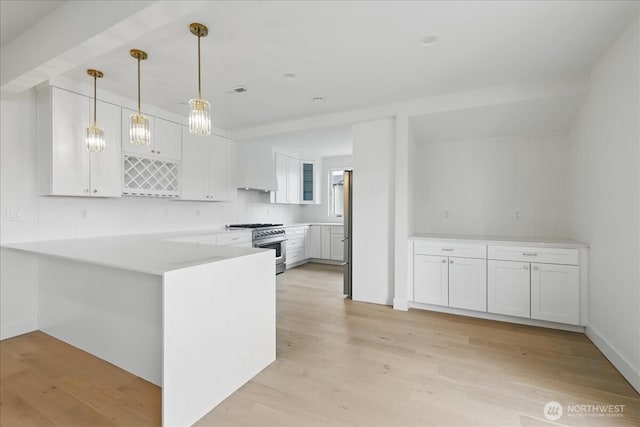 150 Cliff Robinson Ln, Sequim, WA 98382 - kitchen featuring stainless steel appliances, a peninsula, white cabinets, light wood-type flooring, and light countertops