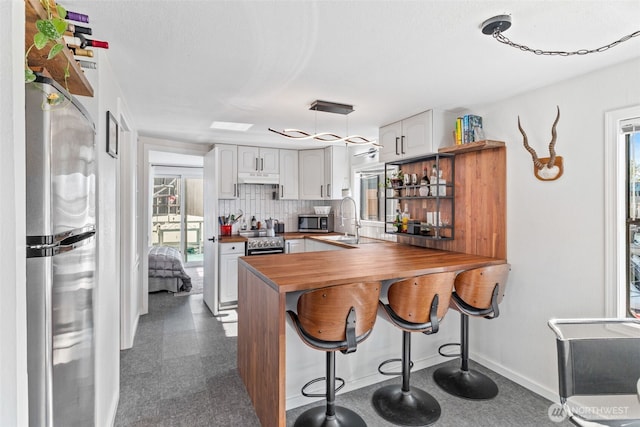 2401 N Northlake Way Unit F6, Seattle, WA 98103 - kitchen with appliances with stainless steel finishes, wood counters, plenty of natural light, and a peninsula