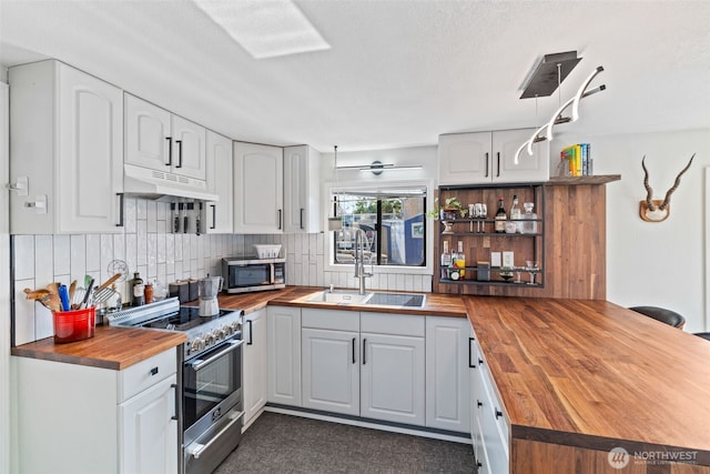 2401 N Northlake Way Unit F6, Seattle, WA 98103 - kitchen with butcher block counters, appliances with stainless steel finishes, under cabinet range hood, a peninsula, and white cabinetry