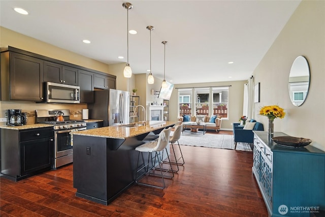 13712 Big Sky Dr E, Bonney Lake, WA 98391 - kitchen featuring stainless steel appliances, dark wood finished floors, open floor plan, light stone countertops, and a kitchen island with sink