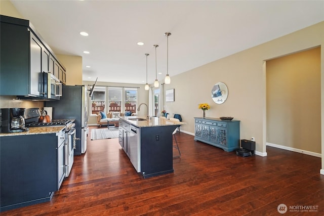 13712 Big Sky Dr E, Bonney Lake, WA 98391 - kitchen featuring appliances with stainless steel finishes, dark wood-style floors, a kitchen breakfast bar, a kitchen island with sink, and light stone countertops