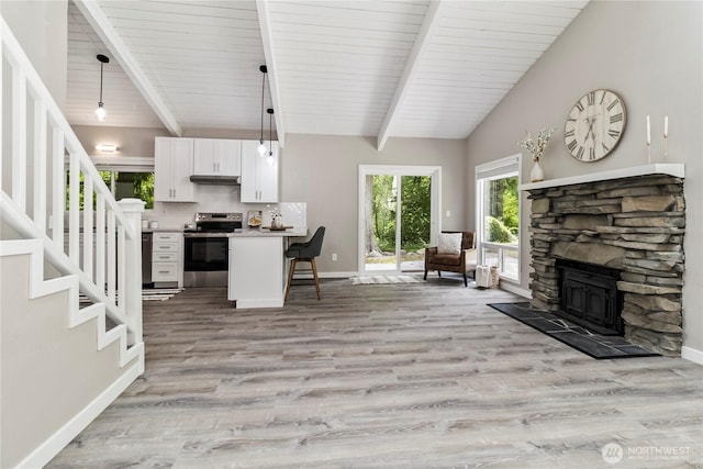 1535 Ten Mile Rd, Everson, WA 98247 - kitchen with electric stove, a breakfast bar, open floor plan, white cabinetry, and under cabinet range hood