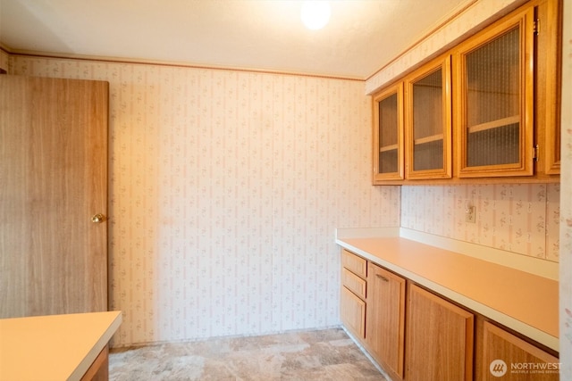37301 28th Ave S Unit 4, Federal Way, WA 98003 - kitchen featuring light countertops, brown cabinets, glass insert cabinets, light carpet, and wallpapered walls