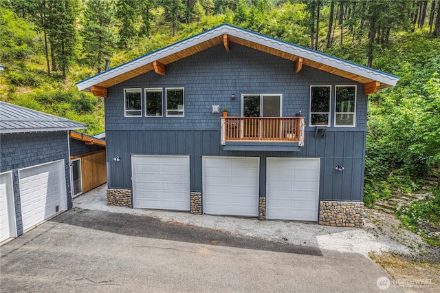 359 Timber Ridge Canyon Rd, Leavenworth, WA 98826 - view of front of property with a balcony, stone siding, a forest view, and driveway