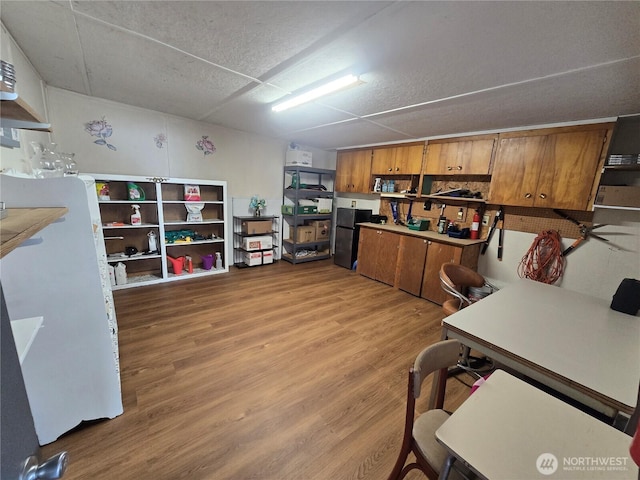836 E Harman Way E Unit 62, Orting, WA 98360 - kitchen with brown cabinetry, freestanding refrigerator, light wood-type flooring, and a desk