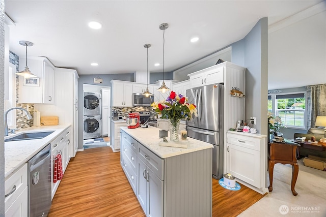 121 E Willapa Rd, Shelton, WA 98584 - kitchen with appliances with stainless steel finishes, stacked washer and clothes dryer, a center island, backsplash, and light wood-style flooring