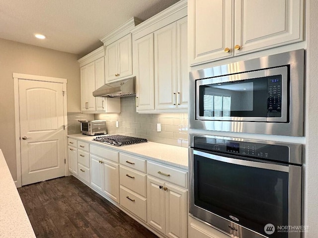 885 N Squire Dr, Ridgefield, WA 98642 - kitchen featuring appliances with stainless steel finishes, under cabinet range hood, light countertops, white cabinetry, and dark wood-style flooring