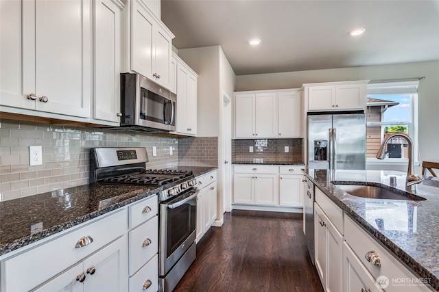 7336 Ashdown Ln SE, Olympia, WA 98513 - kitchen featuring appliances with stainless steel finishes, dark wood-style floors, white cabinetry, dark stone countertops, and backsplash