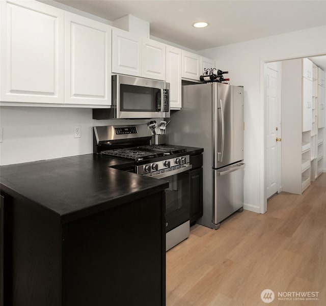 18304 Mclean Rd SW, Vashon, WA 98070 - kitchen with stainless steel appliances, dark countertops, light wood-style floors, white cabinets, and recessed lighting