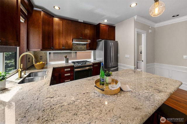 4314 Linden Ave N, Seattle, WA 98103 - kitchen with appliances with stainless steel finishes, under cabinet range hood, crown molding, light stone countertops, and tasteful backsplash