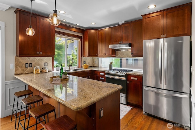 4314 Linden Ave N, Seattle, WA 98103 - kitchen with stainless steel appliances, under cabinet range hood, a peninsula, light stone countertops, and dark wood-style floors