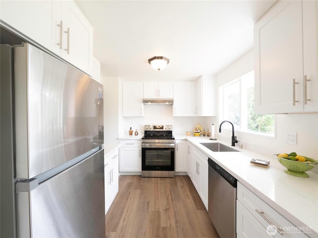 18111 46th Ave S, Seatac, WA 98188 - kitchen with stainless steel appliances, under cabinet range hood, light wood finished floors, light countertops, and white cabinetry