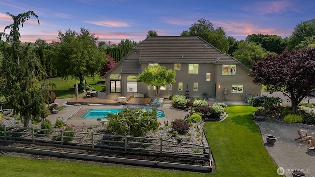 78718 Echols Rd, Hermiston, OR 97838 - back of house at dusk with a deck, an outdoor pool, a patio area, and a tiled roof