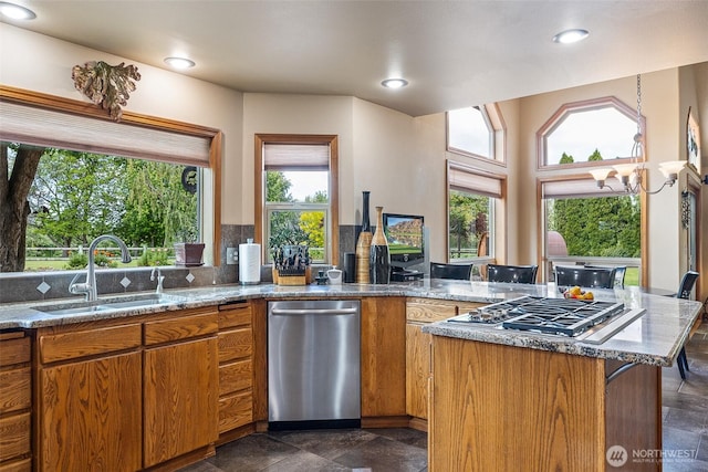 78718 Echols Rd, Hermiston, OR 97838 - kitchen with stainless steel appliances, light stone counters, brown cabinetry, a peninsula, and recessed lighting
