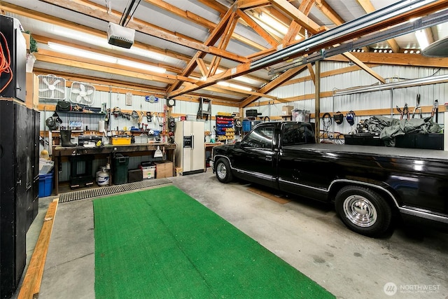 19322 Old Burn Rd, Arlington, WA 98223 - garage featuring a garage door opener, white fridge with ice dispenser, and a workshop area