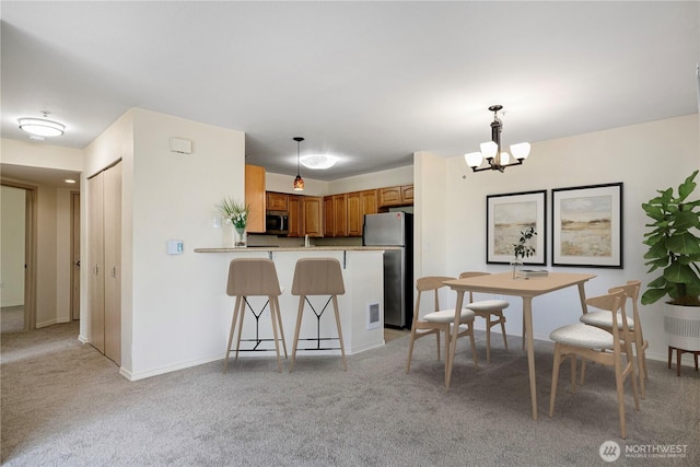 11130 SE 208th St Unit K101, Kent, WA 98031 - kitchen featuring appliances with stainless steel finishes, a peninsula, a chandelier, a kitchen bar, and light colored carpet