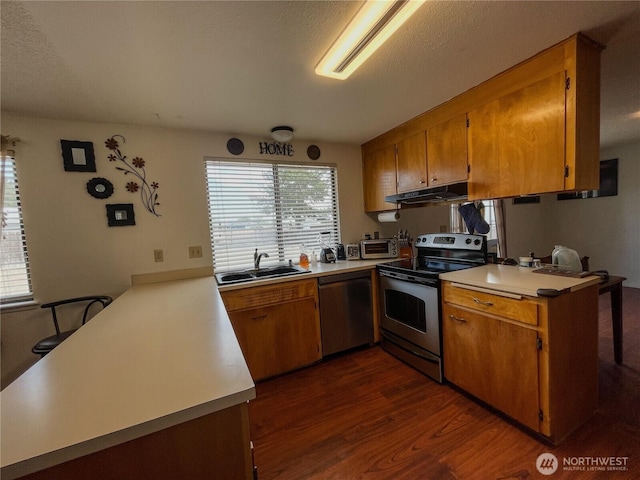 351N Grape, Moses Lake, WA 98837 - kitchen featuring stainless steel appliances, a peninsula, under cabinet range hood, dark wood-style flooring, and brown cabinets