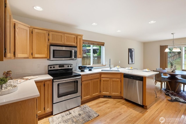 817 Darwins Way, Granite Falls, WA 98252 - kitchen featuring stainless steel appliances, a peninsula, light countertops, backsplash, and light wood finished floors