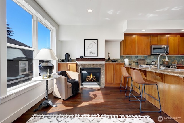 2063 13th Ave W, Seattle, WA 98119 - kitchen featuring stainless steel microwave, light stone countertops, backsplash, brown cabinetry, and recessed lighting