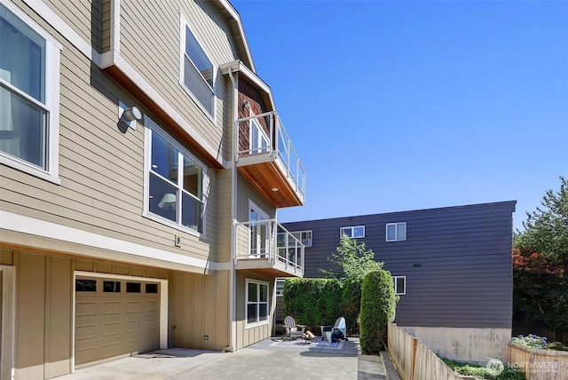 2063 13th Ave W, Seattle, WA 98119 - view of side of home featuring a balcony, board and batten siding, a patio area, and a garage