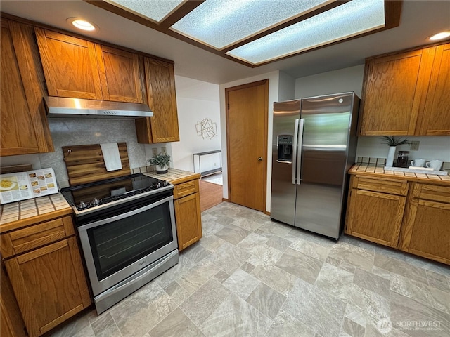 18509 22nd Ave E, Tacoma, WA 98445 - kitchen featuring stainless steel appliances, tile counters, extractor fan, brown cabinets, and recessed lighting