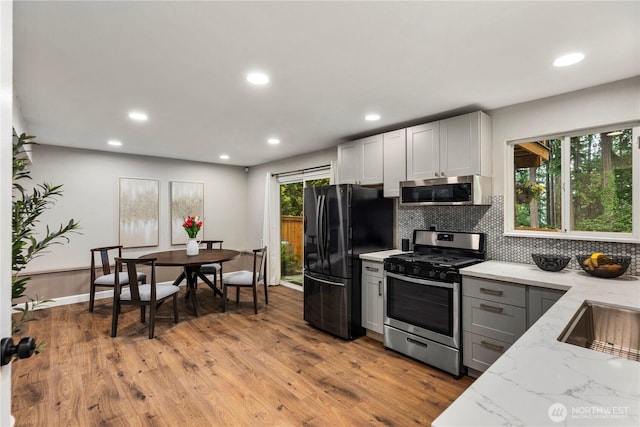 22625 1st Dr SE, Bothell, WA 98021 - kitchen with stainless steel appliances, light stone countertops, recessed lighting, tasteful backsplash, and light wood-style floors