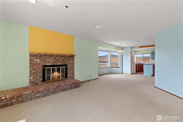 2338 Grand Ave, East Wenatchee, WA 98802 - unfurnished living room featuring a chandelier, light colored carpet, and a brick fireplace