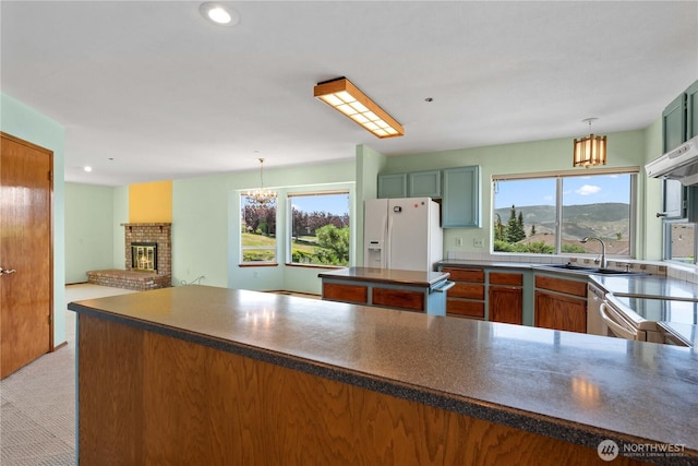 2338 Grand Ave, East Wenatchee, WA 98802 - kitchen featuring white fridge with ice dispenser, dark countertops, plenty of natural light, a brick fireplace, and recessed lighting