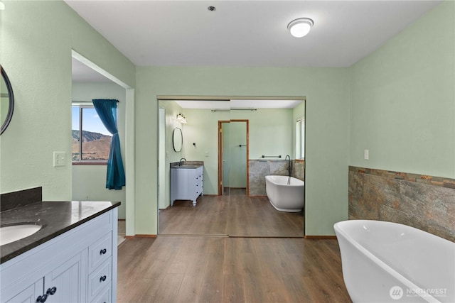2338 Grand Ave, East Wenatchee, WA 98802 - full bath featuring two vanities, tile walls, wood finished floors, a wainscoted wall, and a soaking tub