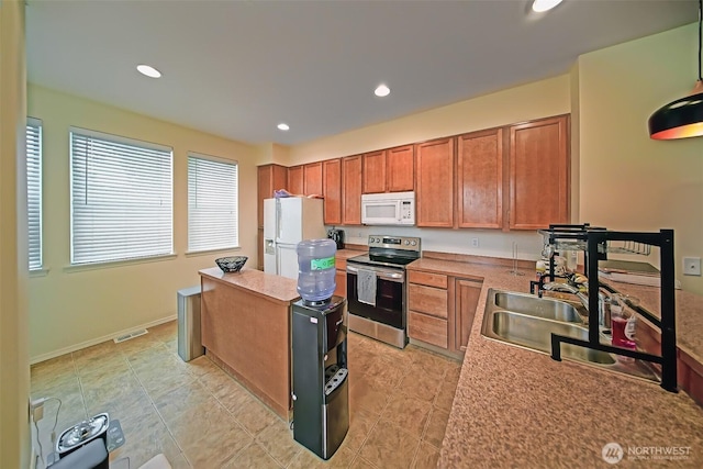 816 Cherry Ave, Sumner, WA 98390 - kitchen featuring white appliances, a center island, brown cabinetry, recessed lighting, and light countertops