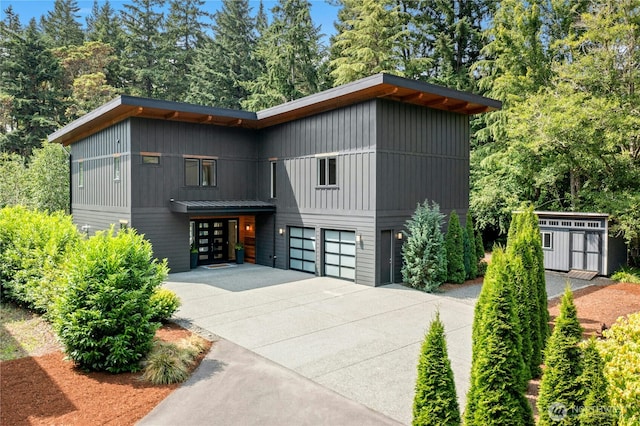 6686 NE Ralston Rd, Bainbridge Island, WA 98110 - contemporary house featuring a garage, driveway, a storage unit, and view of wooded area