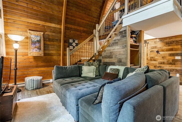14001 Welcome Rd, Glacier, WA 98244 - living room with wood walls, wood finished floors, stairway, vaulted ceiling, and a baseboard radiator